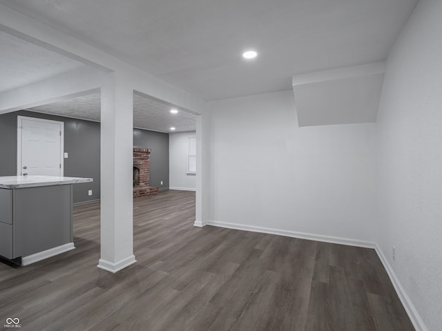 basement featuring a fireplace, a textured ceiling, and dark hardwood / wood-style floors