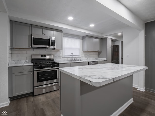 kitchen featuring appliances with stainless steel finishes, a center island, gray cabinetry, and sink