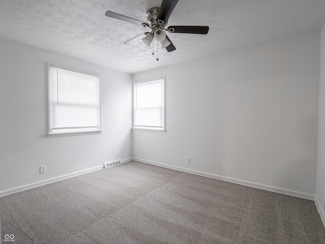 carpeted spare room featuring ceiling fan and a textured ceiling