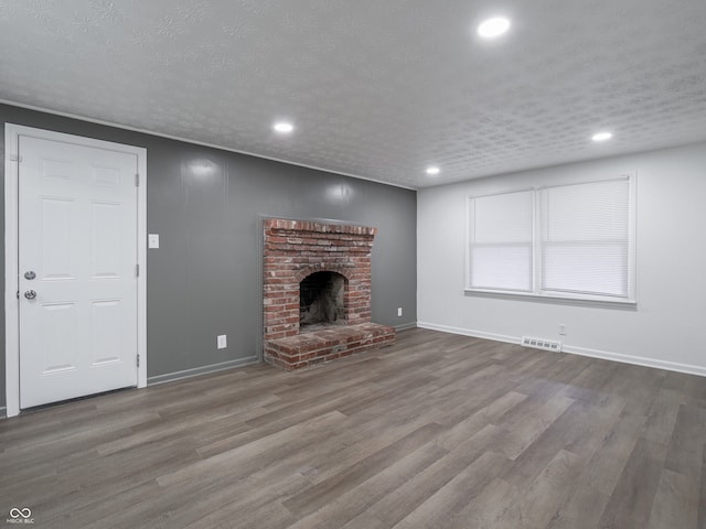 unfurnished living room with a fireplace, wood-type flooring, and a textured ceiling