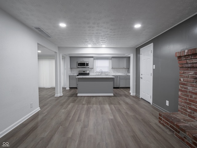 kitchen with gray cabinetry, sink, stainless steel appliances, and a textured ceiling