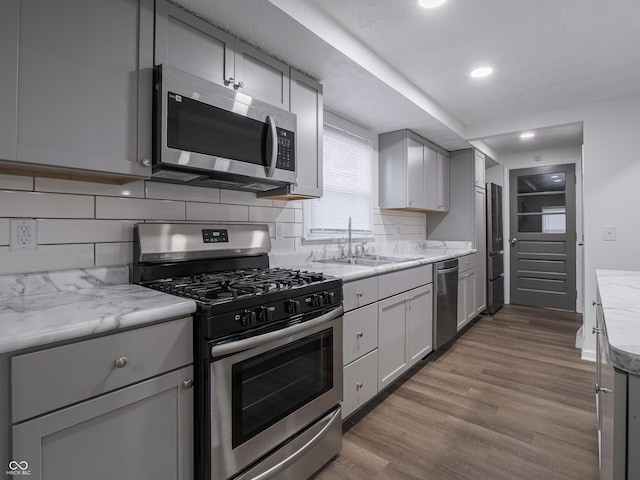 kitchen featuring decorative backsplash, appliances with stainless steel finishes, light hardwood / wood-style floors, and gray cabinetry