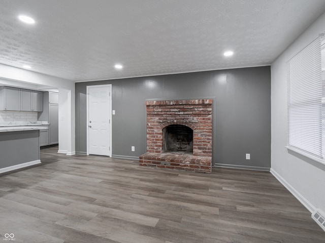 unfurnished living room with a fireplace, dark wood-type flooring, and a textured ceiling