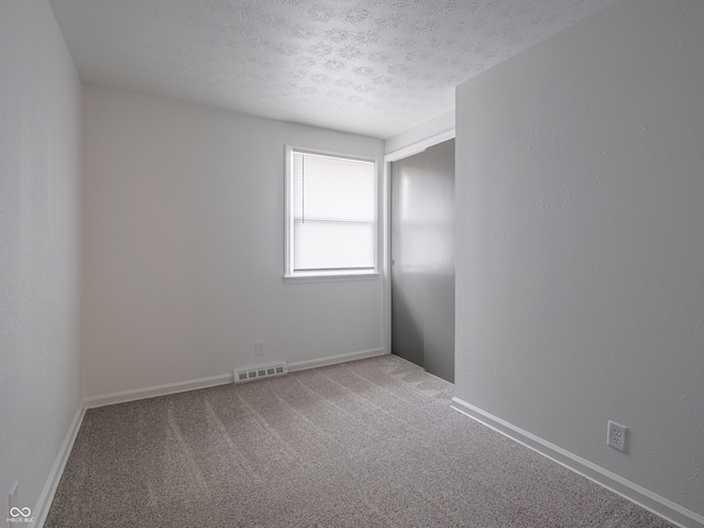 empty room with carpet and a textured ceiling