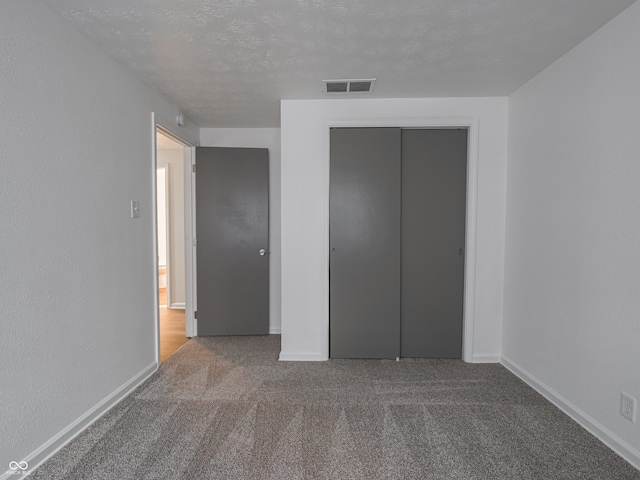 unfurnished bedroom featuring carpet, a textured ceiling, and a closet