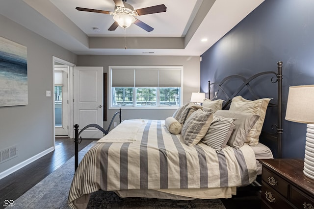 bedroom featuring a tray ceiling, ceiling fan, and dark wood-type flooring