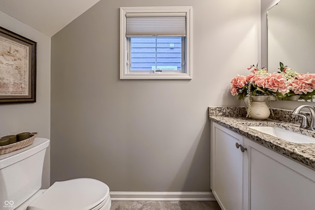 bathroom with vanity, vaulted ceiling, and toilet