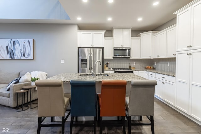 kitchen with a center island with sink, a kitchen breakfast bar, and appliances with stainless steel finishes