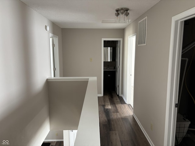 corridor with dark hardwood / wood-style floors, sink, and a textured ceiling