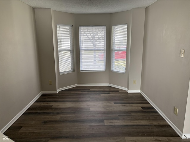 unfurnished room with a textured ceiling and dark wood-type flooring