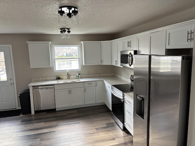 kitchen featuring sink, dark hardwood / wood-style floors, a textured ceiling, white cabinets, and appliances with stainless steel finishes