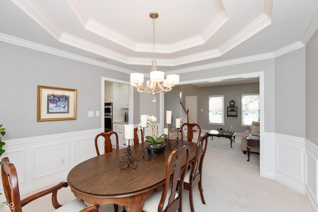 dining area with light colored carpet, a tray ceiling, and a chandelier