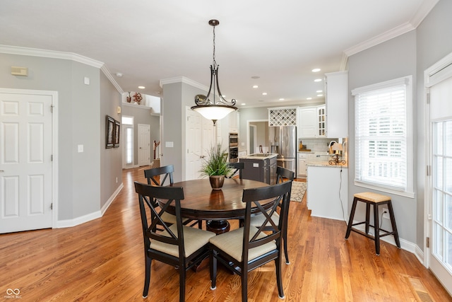 dining space featuring crown molding, sink, and light hardwood / wood-style flooring