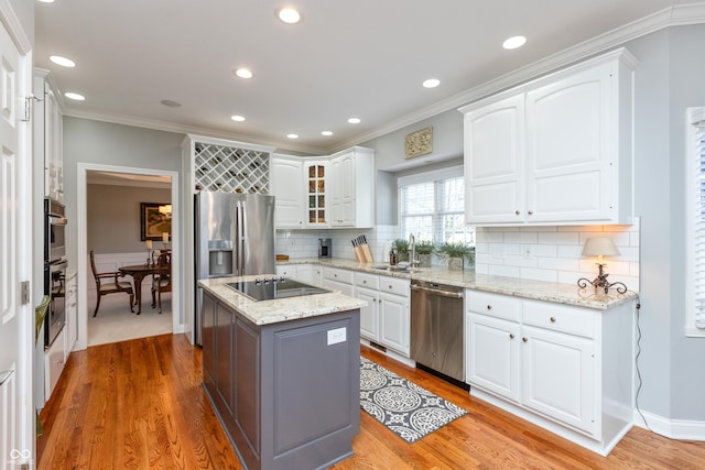 kitchen featuring a kitchen island, appliances with stainless steel finishes, sink, white cabinets, and light stone counters