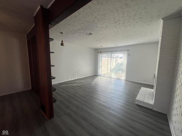 spare room featuring a textured ceiling and dark hardwood / wood-style floors