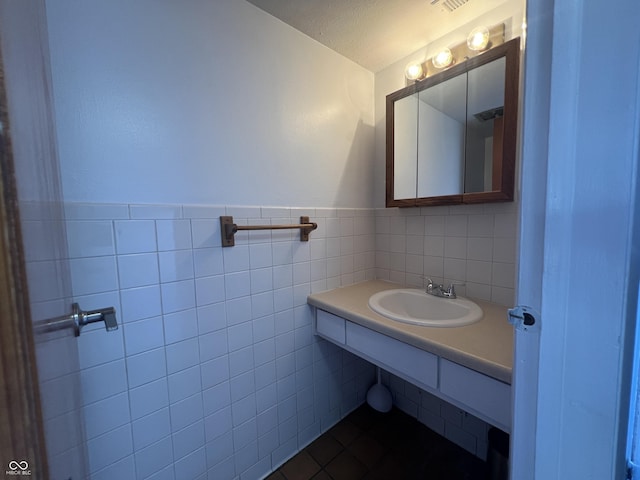 bathroom with tile patterned flooring, sink, and tile walls