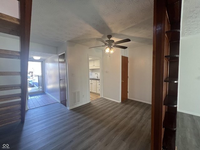 unfurnished room featuring ceiling fan, sink, dark wood-type flooring, and a textured ceiling