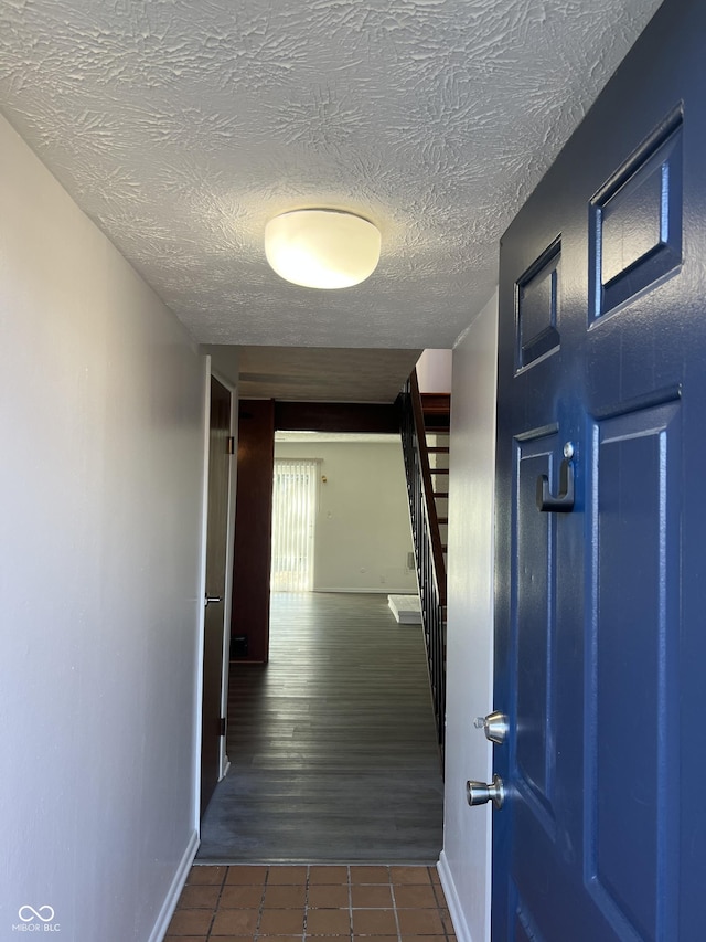 hallway with dark tile patterned flooring and a textured ceiling