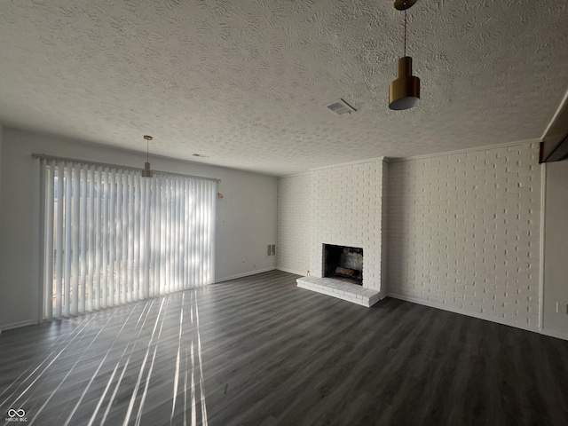 unfurnished living room with a fireplace, a textured ceiling, dark hardwood / wood-style flooring, and brick wall