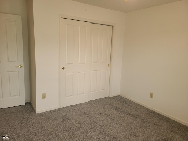 unfurnished bedroom with dark carpet and a closet