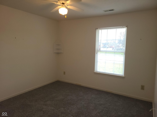 spare room with dark colored carpet and ceiling fan