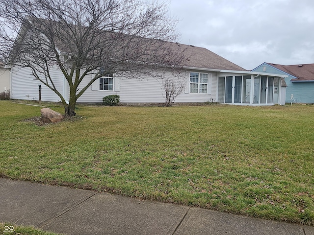 view of home's exterior with a sunroom and a yard