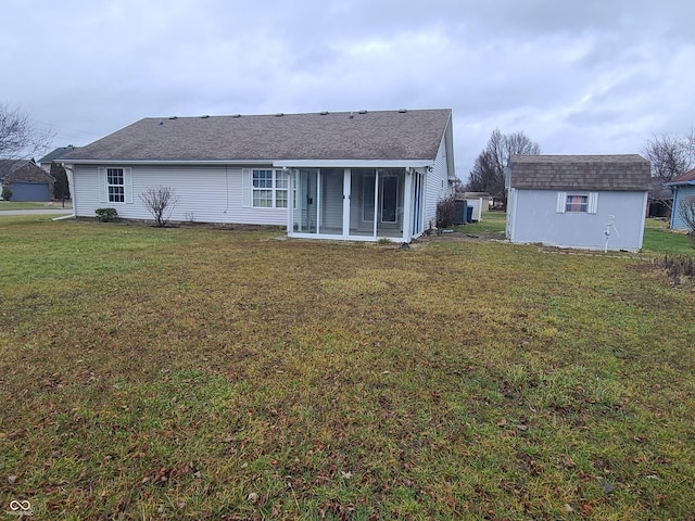 back of house featuring a lawn, a sunroom, and a storage unit