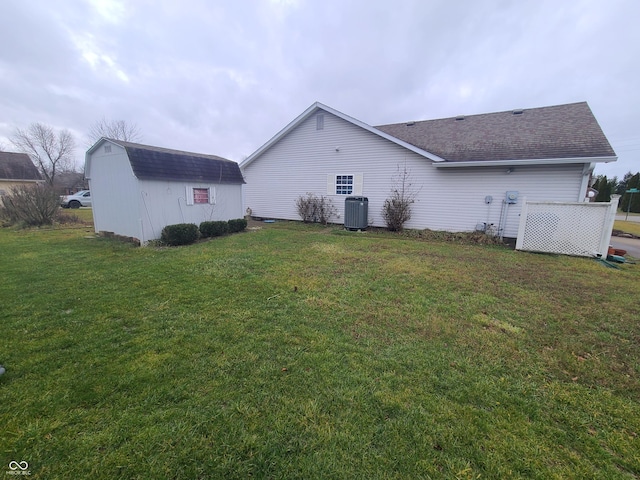 rear view of property featuring a yard, a storage shed, and central air condition unit