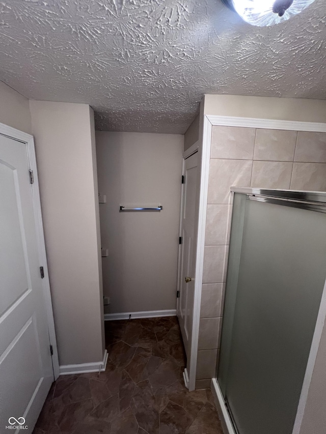 bathroom with a shower with door and a textured ceiling