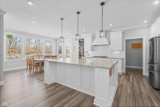 kitchen featuring tasteful backsplash, ornamental molding, stainless steel appliances, custom exhaust hood, and white cabinetry