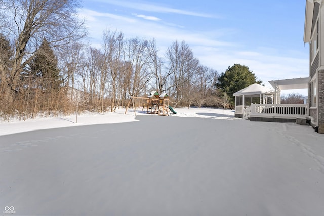 yard covered in snow with a playground and a deck