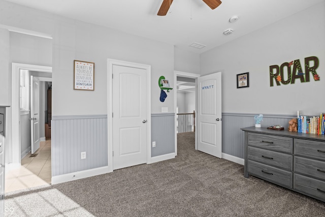 bedroom with carpet, a wainscoted wall, and ceiling fan