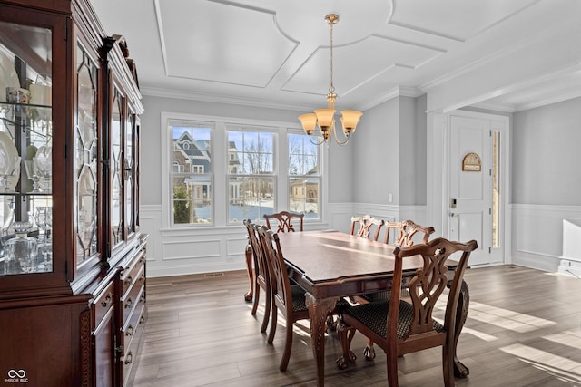 dining room featuring dark wood finished floors, a notable chandelier, wainscoting, and crown molding