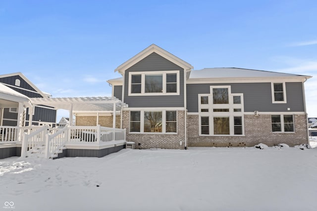 snow covered rear of property featuring a pergola and a wooden deck