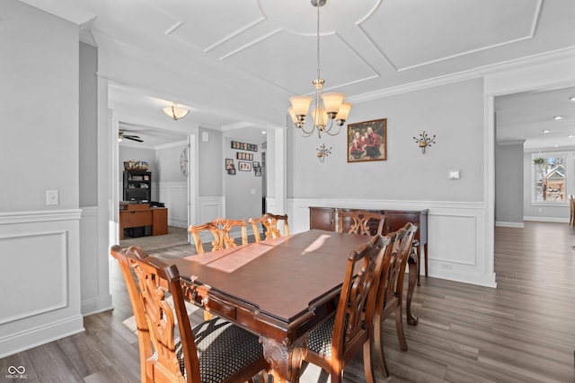 dining room with ceiling fan with notable chandelier, ornamental molding, and dark wood-type flooring