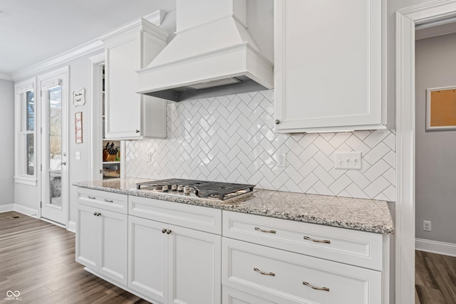 kitchen featuring premium range hood, dark wood-type flooring, light stone counters, white cabinetry, and stainless steel gas stovetop