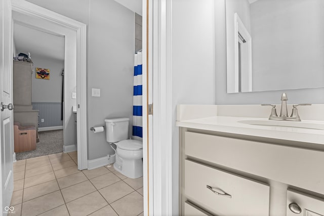 bathroom with tile patterned floors, a shower with curtain, toilet, wainscoting, and vanity