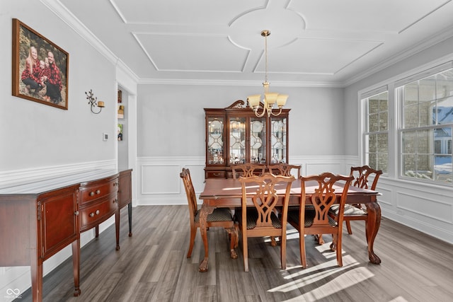 dining space featuring a chandelier, a wainscoted wall, crown molding, and wood finished floors