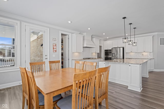 dining room with hardwood / wood-style flooring, sink, and ornamental molding