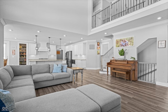 living room featuring dark hardwood / wood-style flooring, a towering ceiling, and ornamental molding