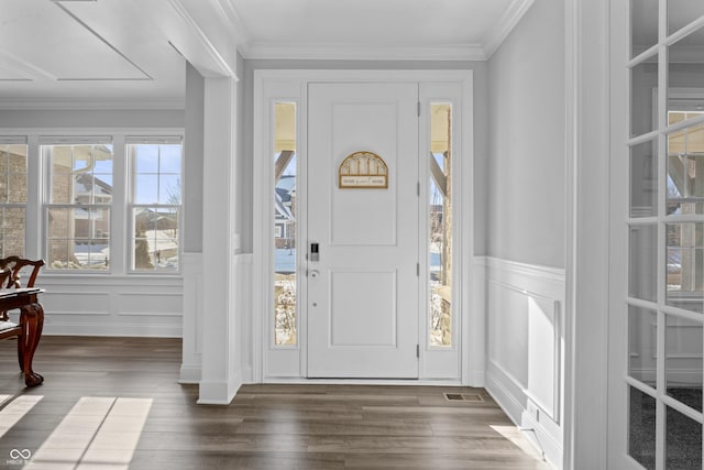 foyer entrance with dark wood-type flooring, a decorative wall, and ornamental molding