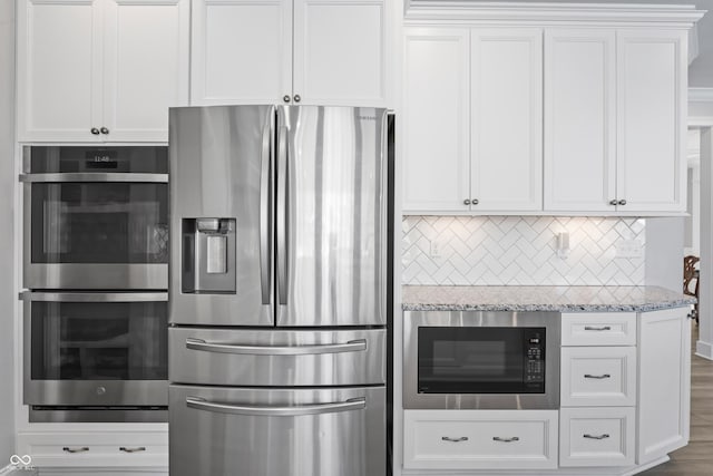 kitchen featuring light stone countertops, appliances with stainless steel finishes, and white cabinetry