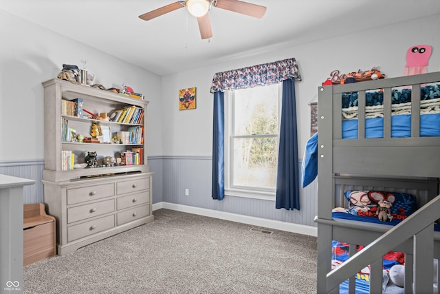 bedroom featuring visible vents, carpet, a wainscoted wall, and ceiling fan