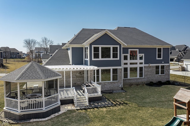 rear view of house featuring a lawn, a playground, a gazebo, a wooden deck, and brick siding