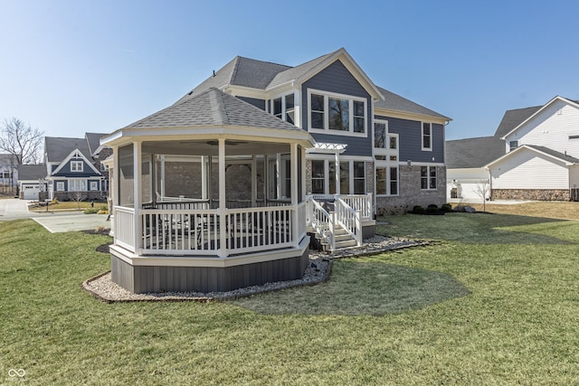 back of house with a lawn, roof with shingles, and a sunroom