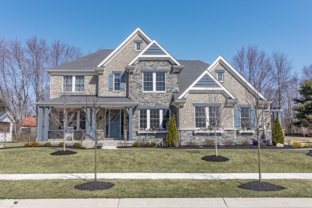 craftsman inspired home with a front lawn, a porch, and stone siding