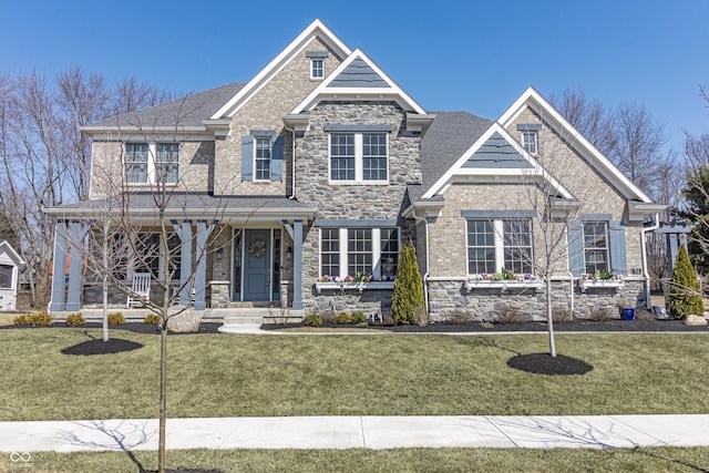 craftsman-style home featuring stone siding, covered porch, and a front lawn