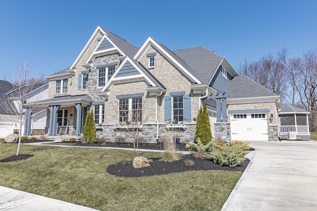 craftsman house with a front yard, covered porch, a garage, stone siding, and driveway