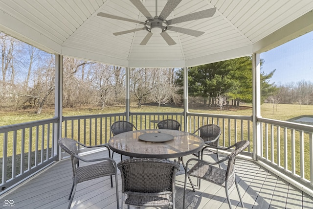 wooden terrace with outdoor dining area, a yard, and a ceiling fan