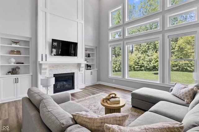 78 Chatham Brook Dr, Westfield, IN 46074 - living room with a high ceiling, wood finished floors, a stone fireplace, built in shelves, and baseboards
